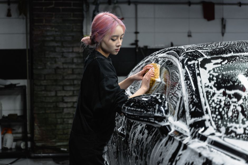 Professional car wash worker inspecting a clean vehicle